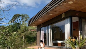 Una casa moderna con un amplio ventanal, una terraza de madera y una planta en maceta.