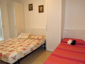 Un dormitorio con dos camas, una con cubrecama floral y la otra con cubrecama a rayas. Hay dos cuadros en la pared.
