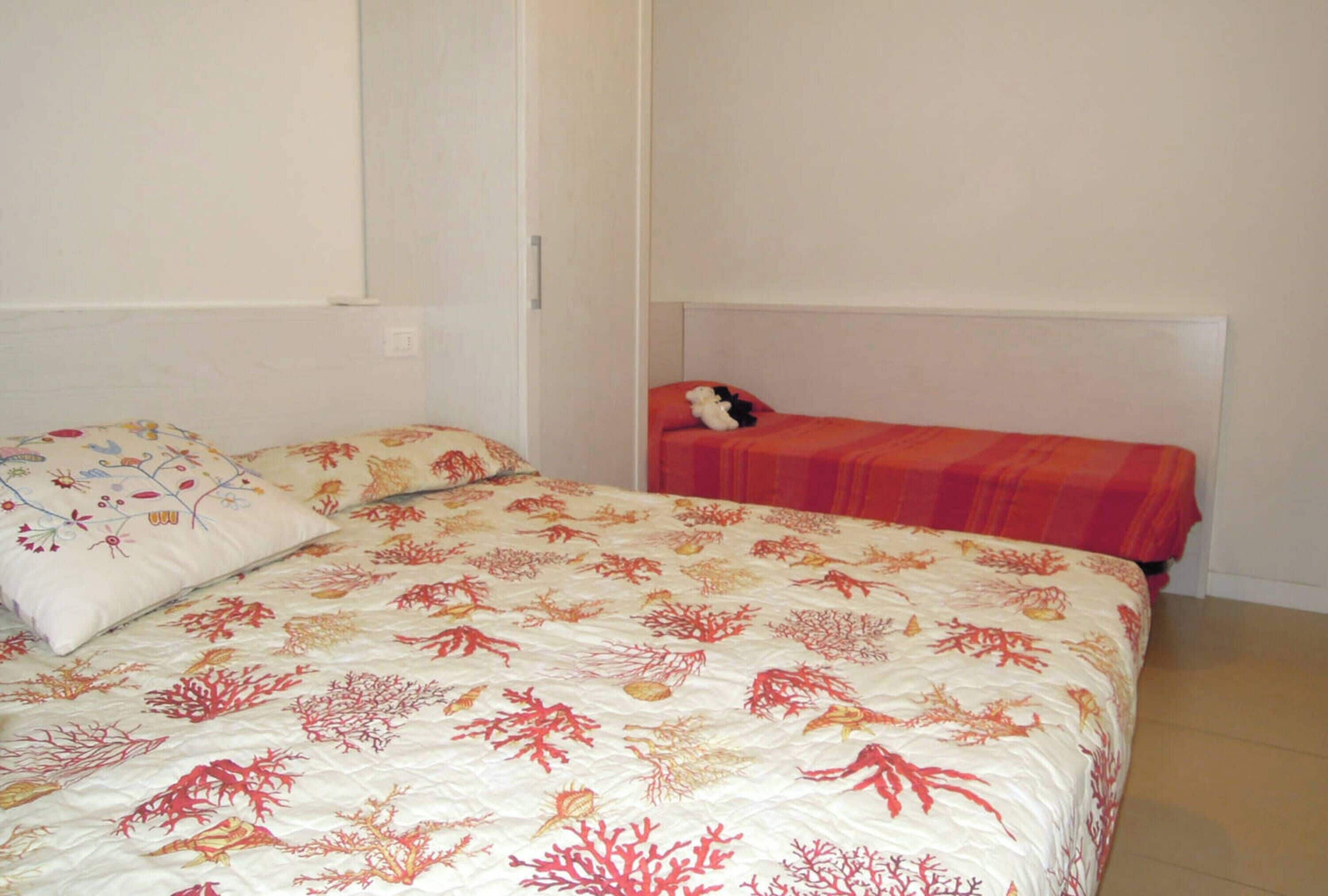A bedroom with a large bed, a smaller bed, and a nightstand.