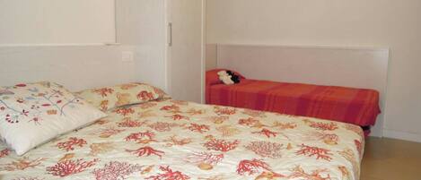 A bedroom with a large bed, a smaller bed, and a nightstand.