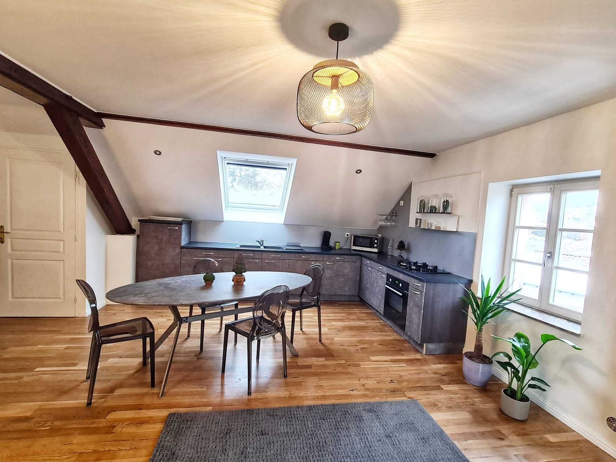 Une cuisine moderne avec un coin repas, un plancher en bois et une lucarne.