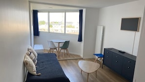 A bedroom with a bed, a desk, a chair, and a TV. - Appartement T2 Refait à Neuf (Cabourg)