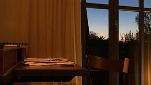 Een kamer met een groot raam, een bureau en een stoel.