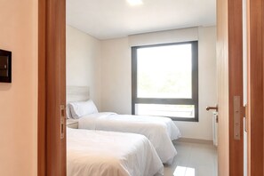 Un dormitorio con dos camas, un ventanal grande y una puerta.