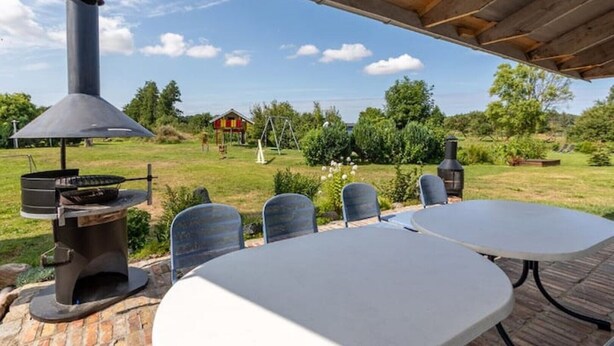 Eine Terrasse im Freien mit Grill, Tisch und Stühlen.