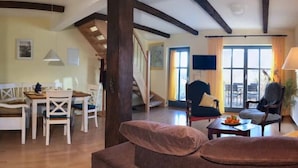 Ein gemütliches Wohnzimmer mit einer Couch, einem Esstisch mit Stühlen und einer Treppe, die in eine weitere Ebene führt.