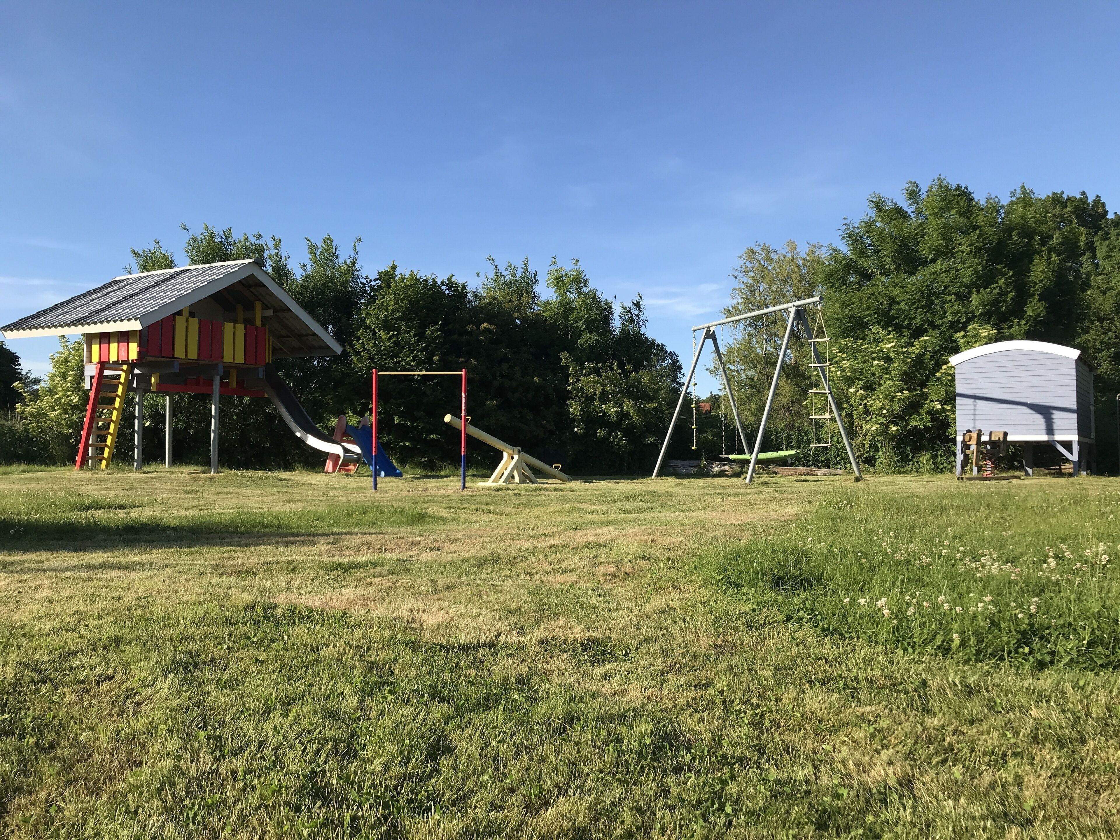 A playground with a slide, swing set, and climbing structure.