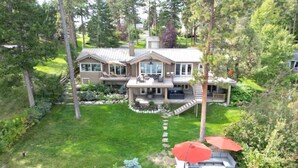 Une grande maison avec un vaste jardin, un patio couvert et une pelouse bien entretenue.