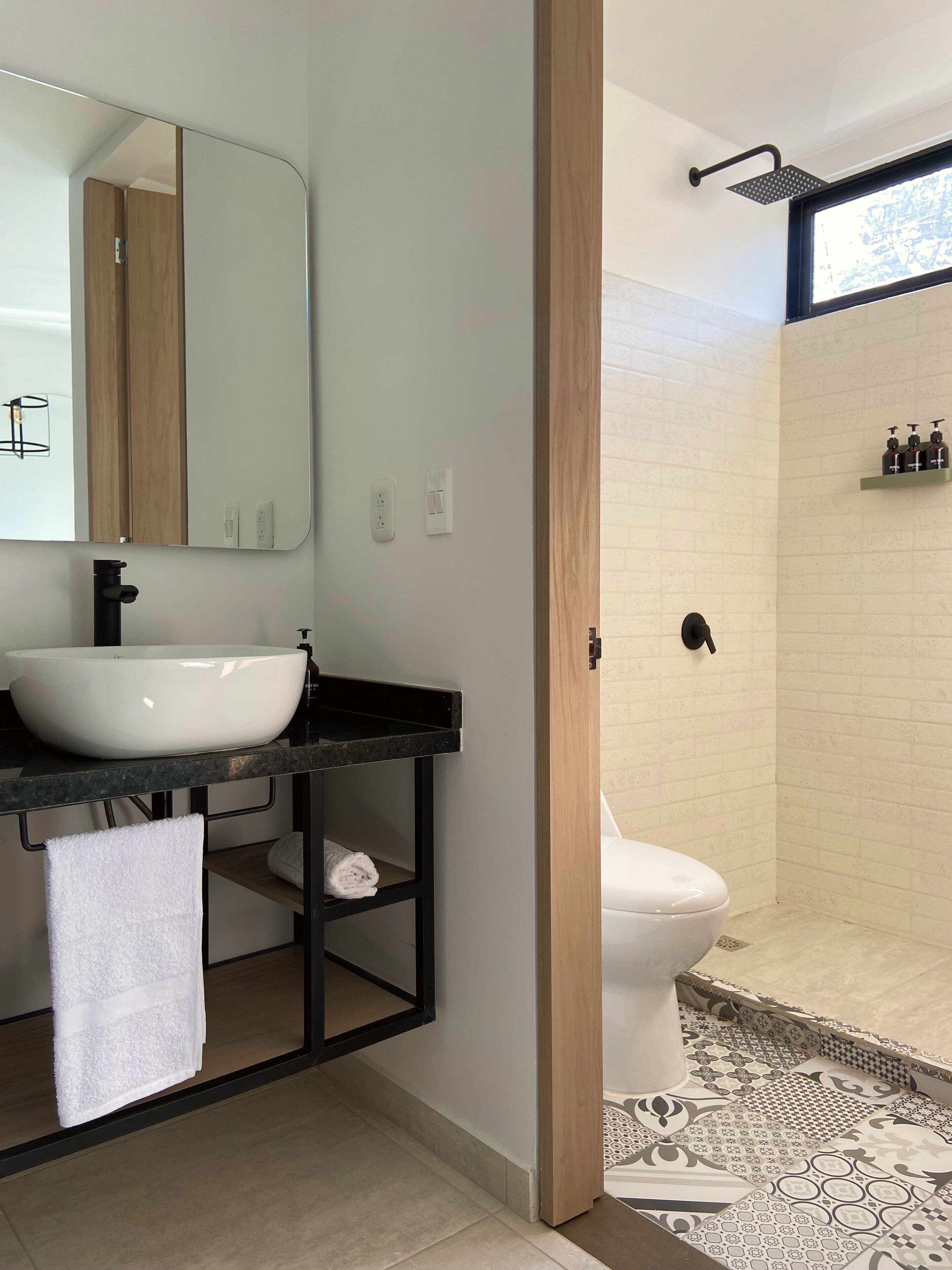 A modern bathroom with a white sink, black countertop, and a large mirror.