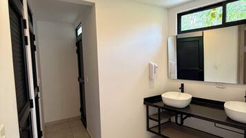 Ein modernes Badezimmer mit einem schwarzen Waschtisch, zwei Waschbecken, einem Spiegel und Einbaustrahler.
