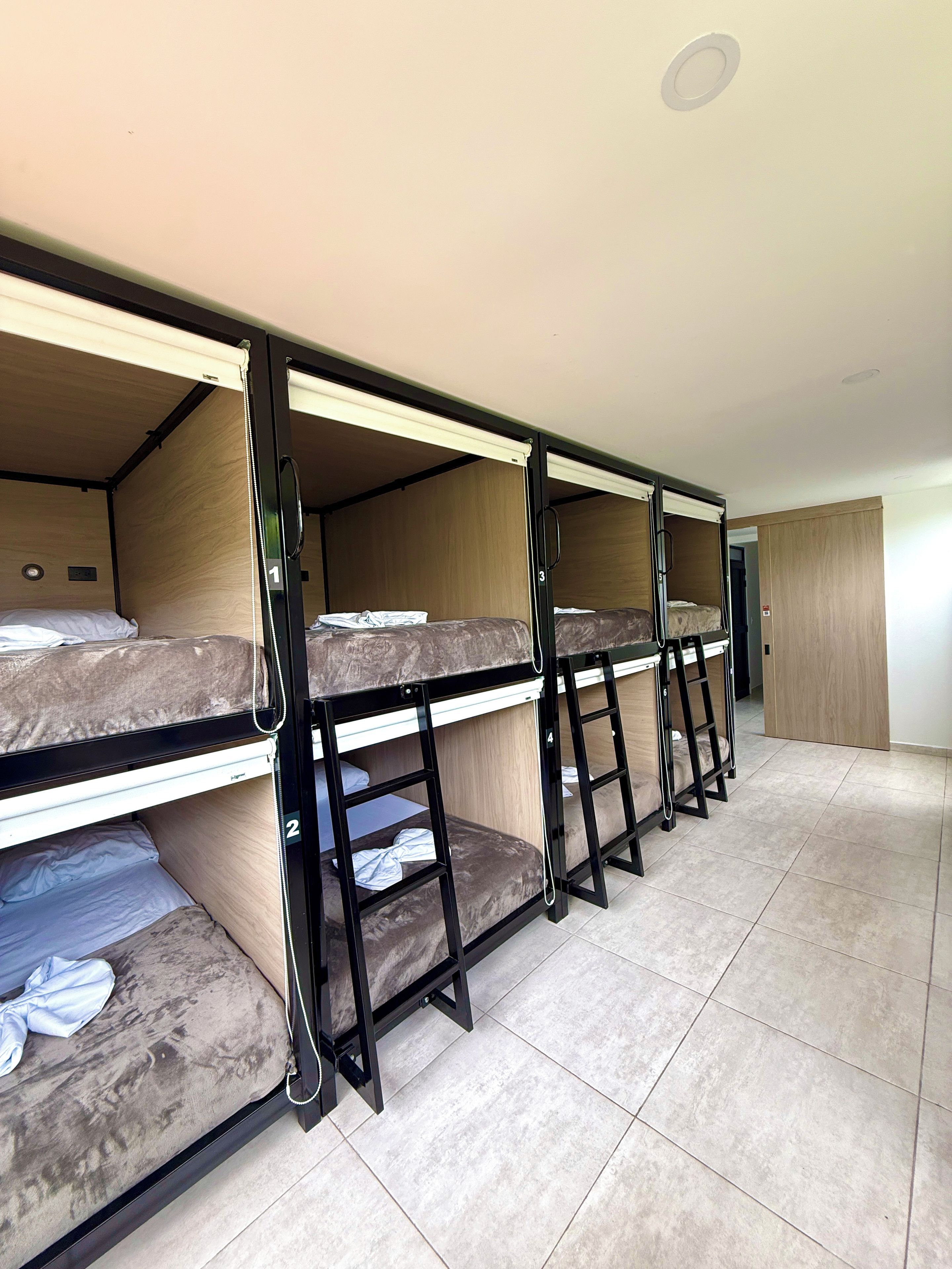 A room with bunk beds, a wooden door, and tiled flooring.