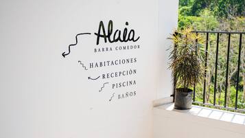 Una mujer bajando una escalera con un cartel que indica servicios como bar, comedor, habitaciones, recepción, piscina y baños.