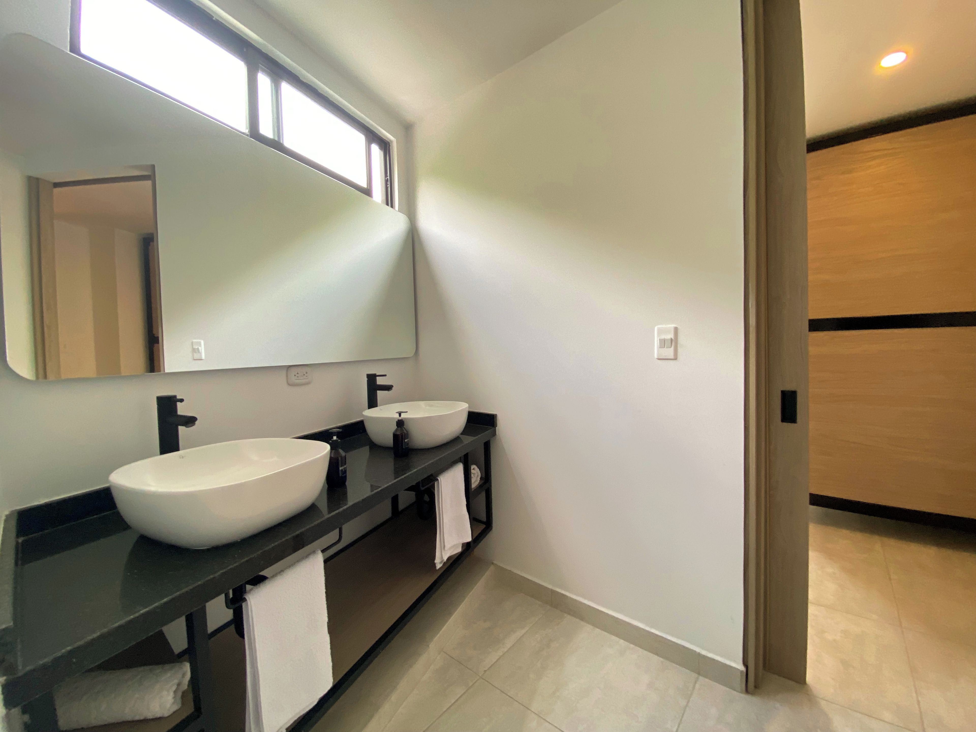 Une salle de bain moderne avec deux lavabos, un grand miroir et un porte-serviettes.