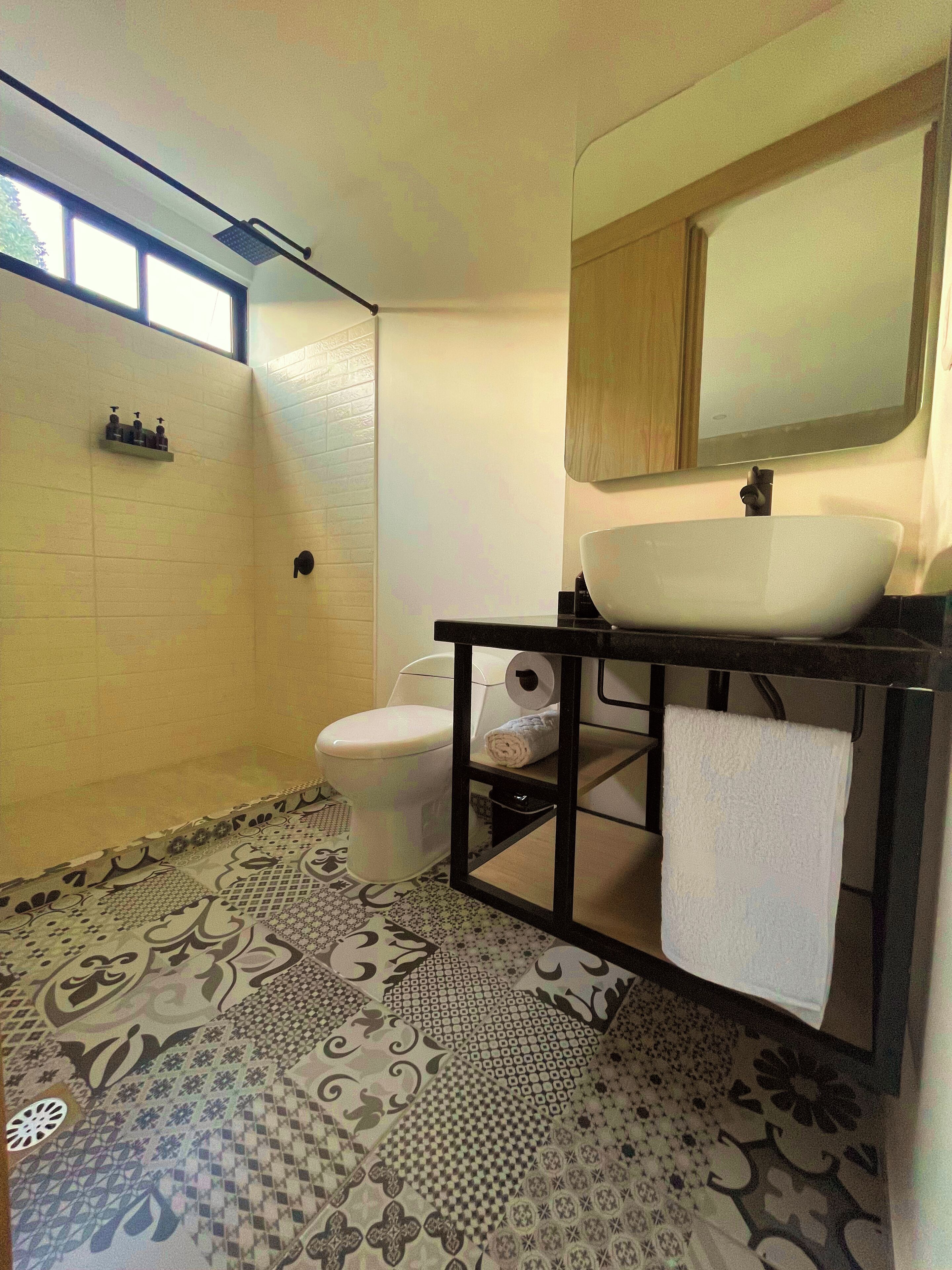 A bathroom with a white sink, a mirror, a toilet, and a shower area.