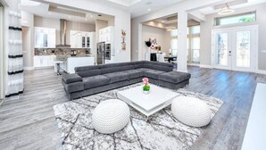 A spacious living area with a sectional sofa, a white coffee table, and two white poufs. - Venice 3 bedroom contemporary home with pool/spa and close to beautiful beaches (Venice)