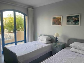 Een hotelkamer met een bed, een nachtkastje, een lamp en twee schilderijen aan de muur.