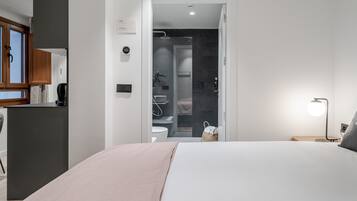 A modern hotel room with a bed, bedside table, and a view into the bathroom.
