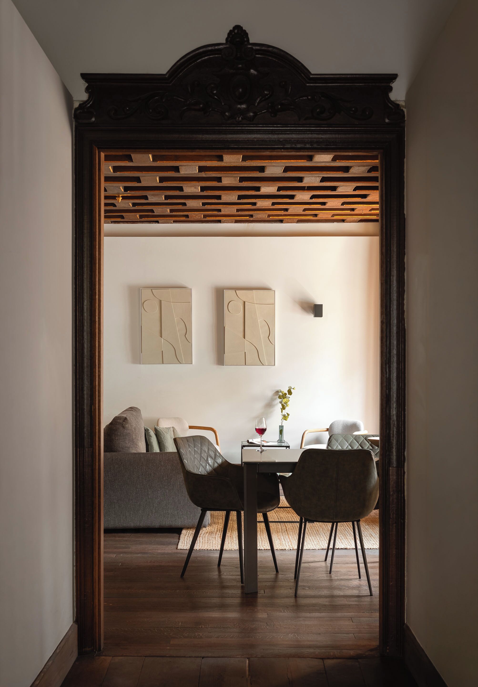 Un pasillo que conduce a un comedor con una mesa, sillas, un sofá y arte abstracto en la pared.