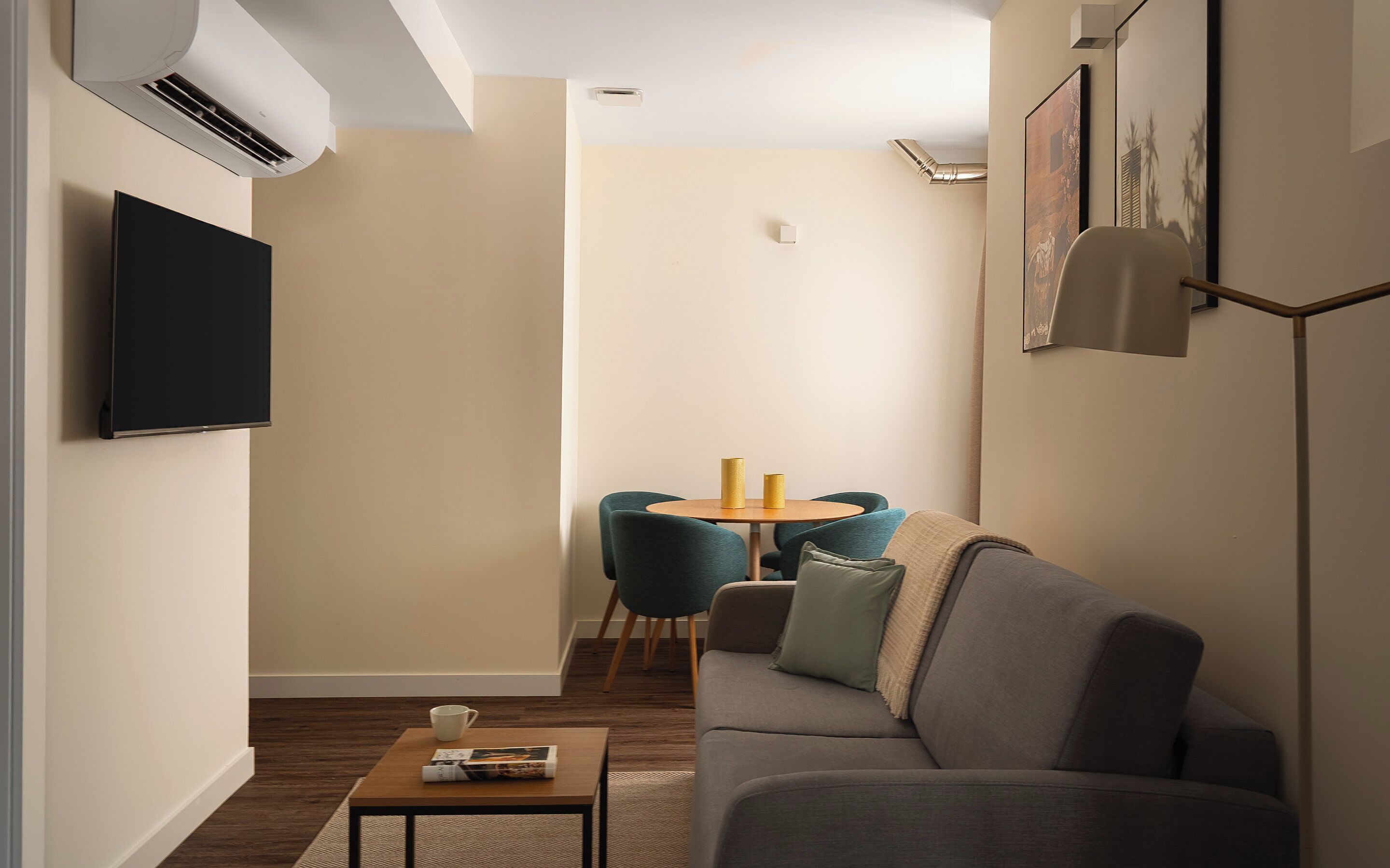 A modern living room with a sofa, a coffee table, a TV, and a dining area with chairs and a table.