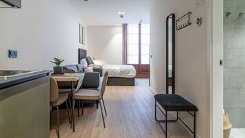Una habitación de hotel moderna y compacta con kitchenette, comedor, cama y baño.