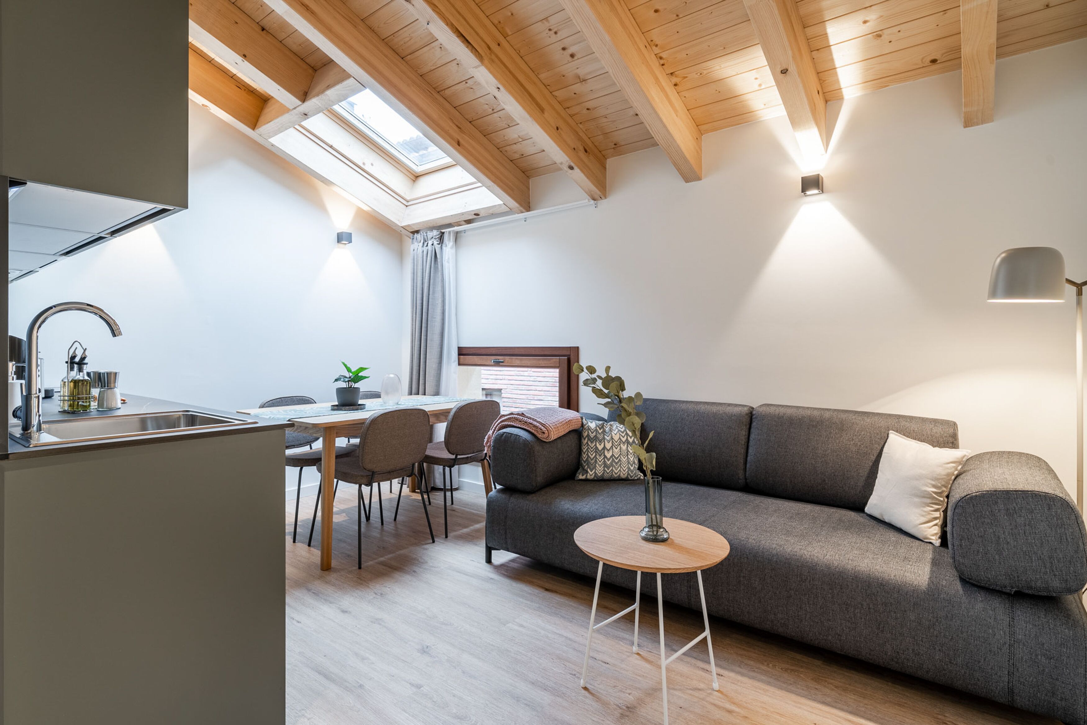 A modern living space with a dining area, a sofa, and a small table.