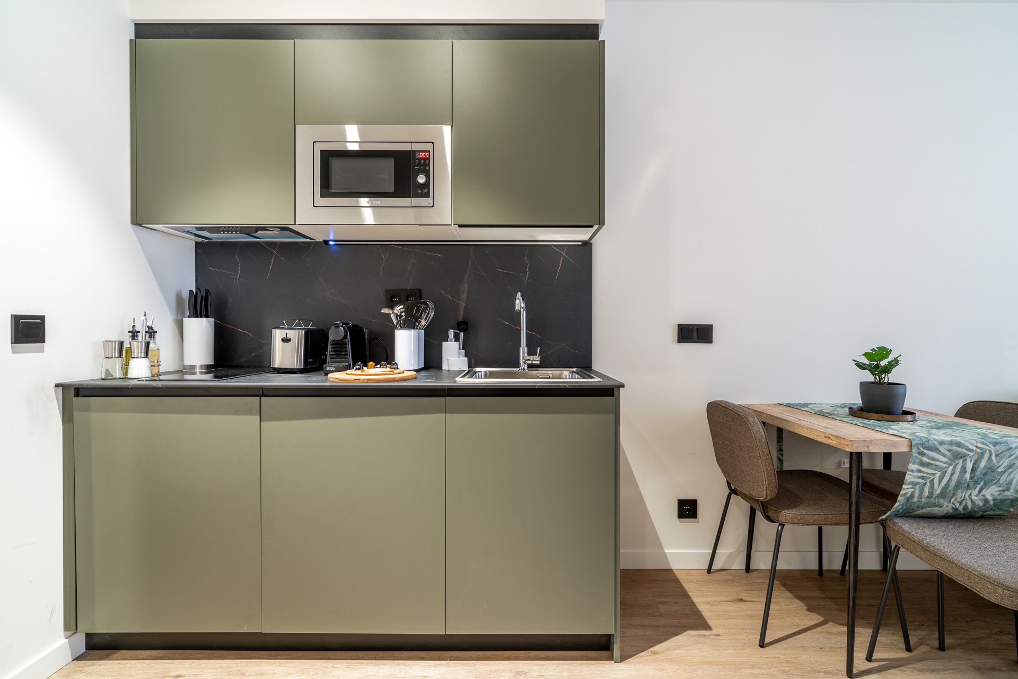 Eine moderne Küche mit Einbau-Mikrowelle, Kaffeemaschine und Spüle.