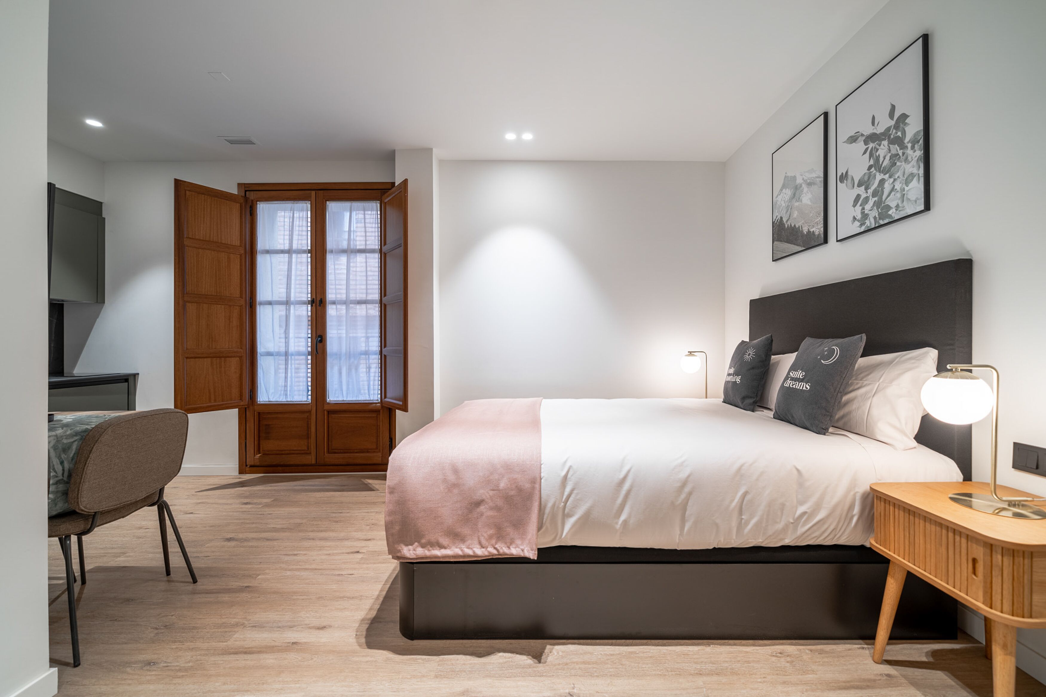Une chambre moderne comprenant un lit, une table de chevet, une chaise et une porte donnant sur un balcon.