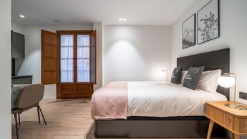 Une chambre moderne comprenant un lit, une table de chevet, une chaise et une porte donnant sur un balcon.
