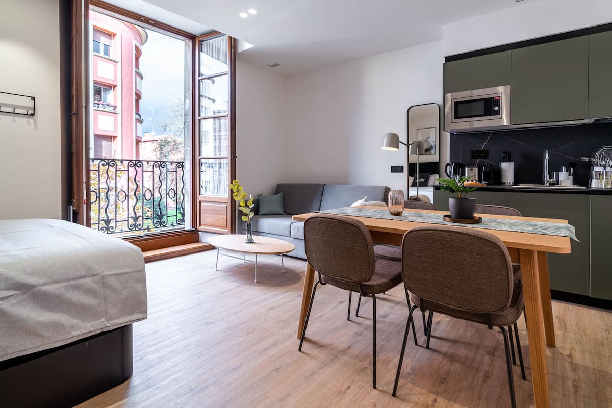 A modern apartment with a dining area, a sofa, and a kitchen.