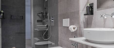 A modern bathroom with a glass-enclosed shower, a toilet, a sink, and a mirror.