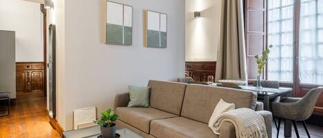 Una sala moderna con un sofá, una mesita de centro y un comedor con una mesa y sillas.