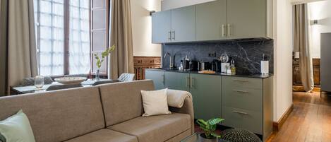 A modern living room with a sofa, a coffee table, and a kitchen area with cabinets and a countertop.