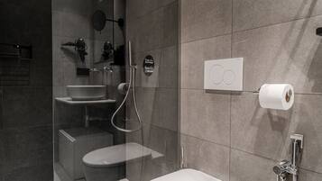 A modern bathroom with a glass-enclosed shower, a white toilet, and a wall-mounted toilet paper dispenser.