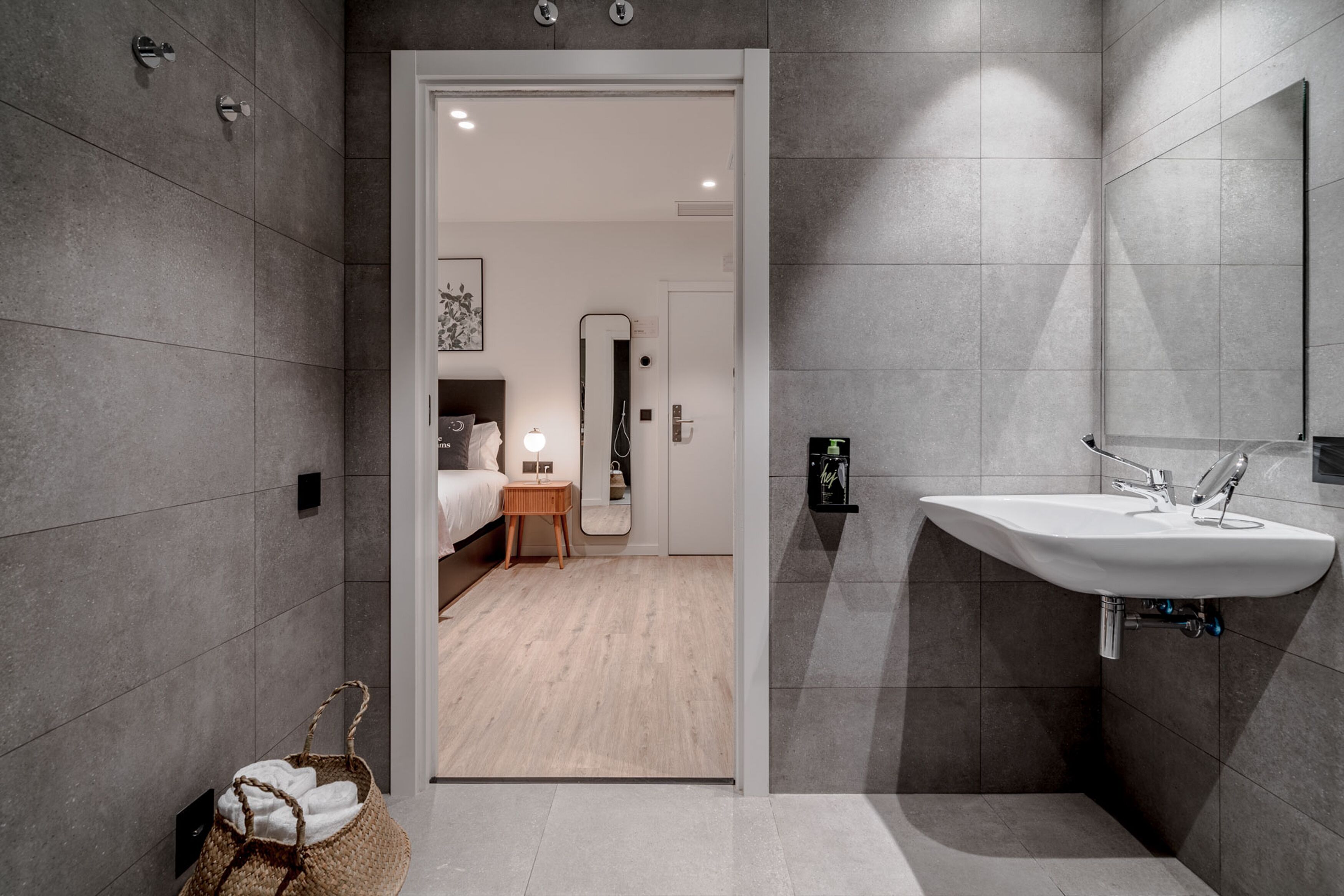 A modern bathroom with a large mirror, a sink, and a wooden floor.