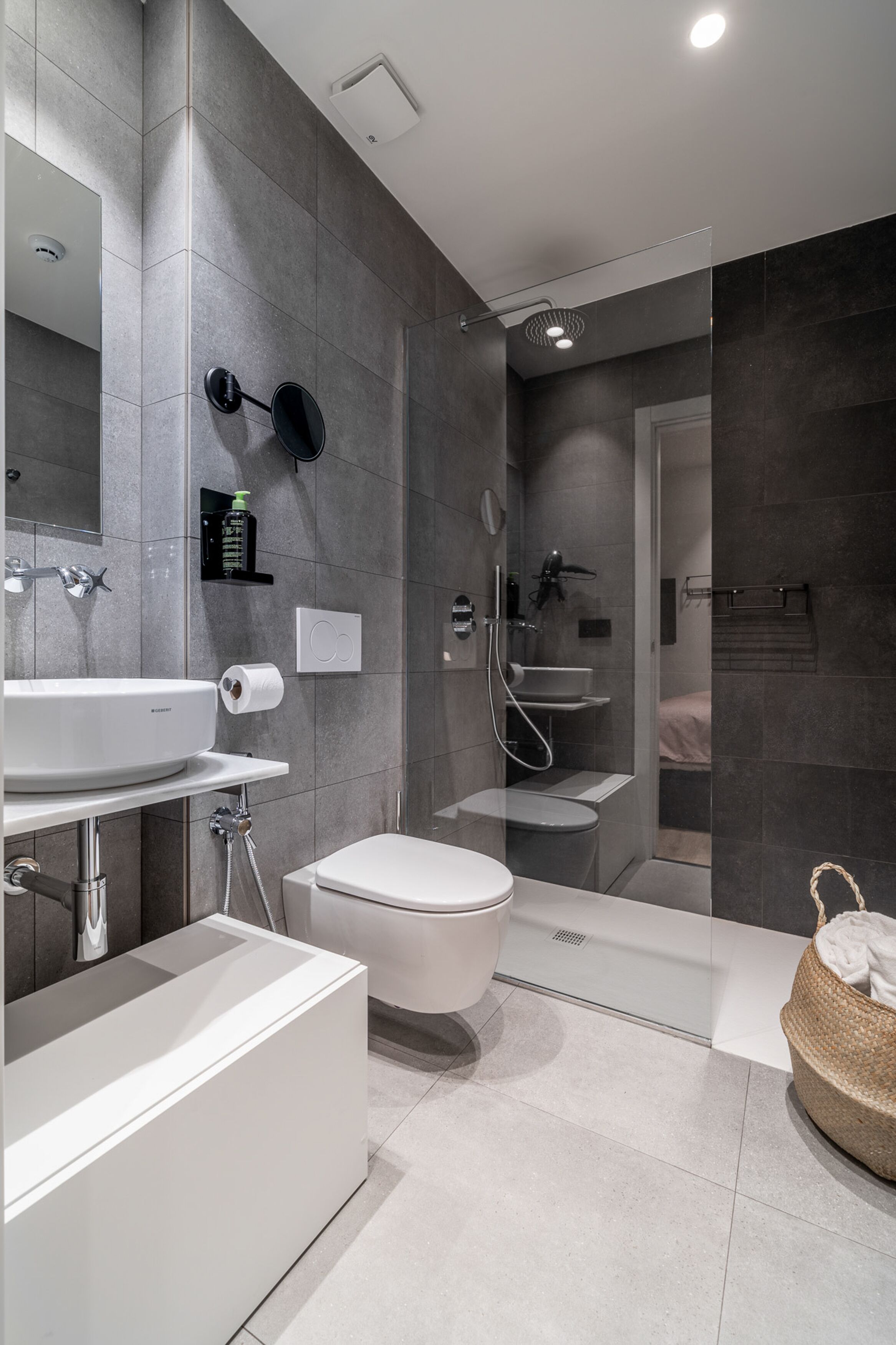 A modern bathroom with a white sink, toilet, and bathtub, a shower area, and a large mirror.