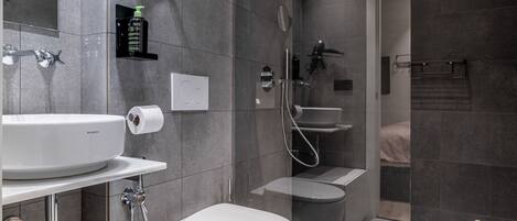 A modern bathroom with a white sink, toilet, and bathtub, a shower area, and a large mirror.