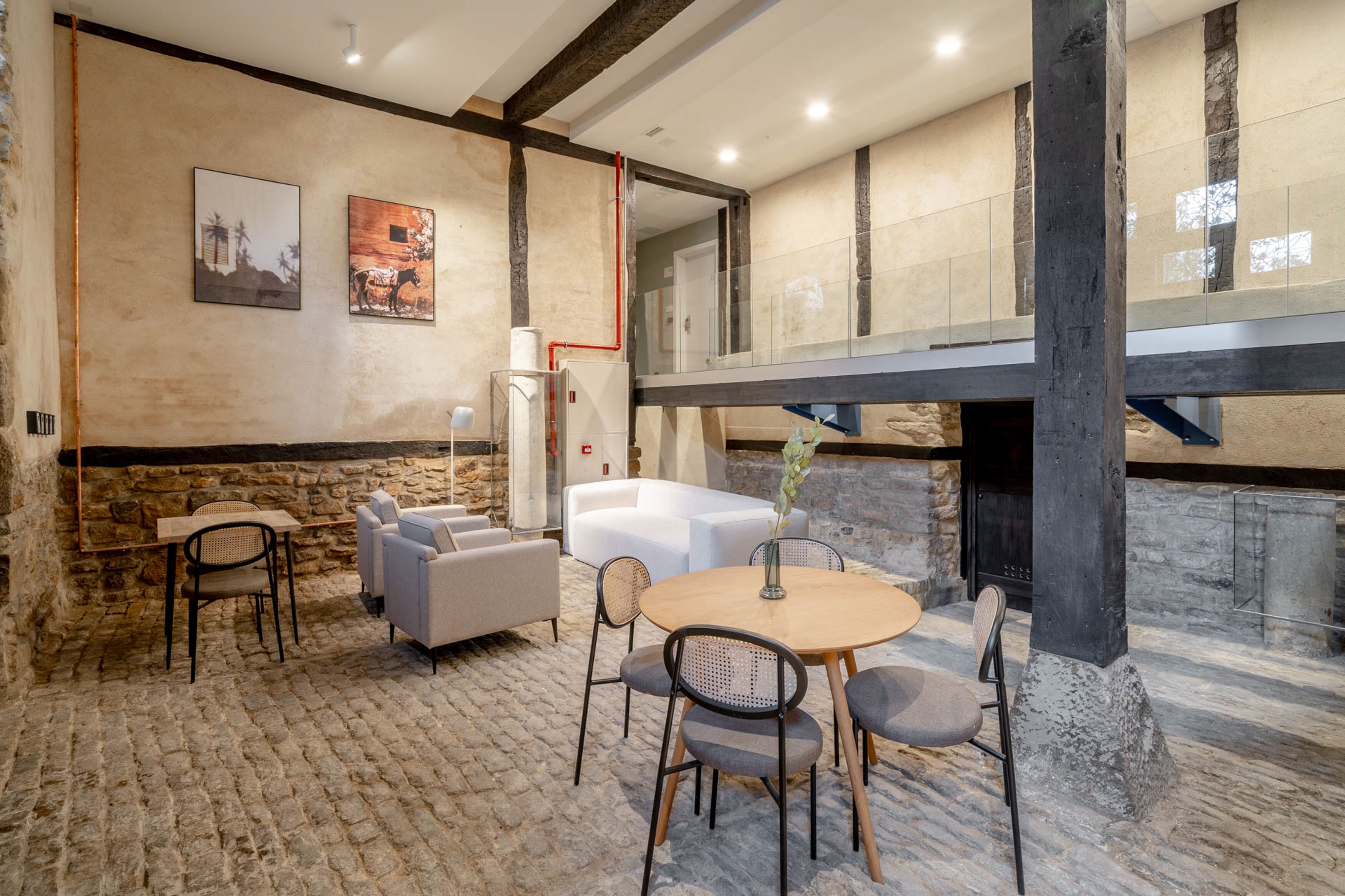 Un interior acogedor con pared de piedra, una mesa de madera con sillas, un sofá blanco y una chimenea.