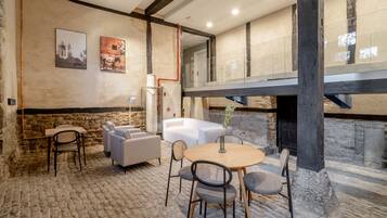 Un interior acogedor con pared de piedra, una mesa de madera con sillas, un sofá blanco y una chimenea.