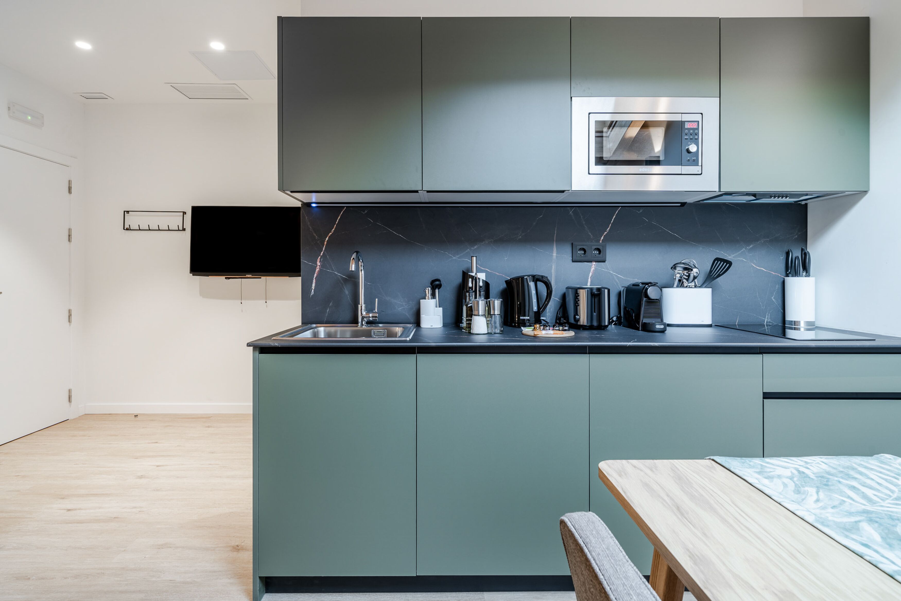 A modern kitchen with a built-in microwave, a sink, and a coffee maker.