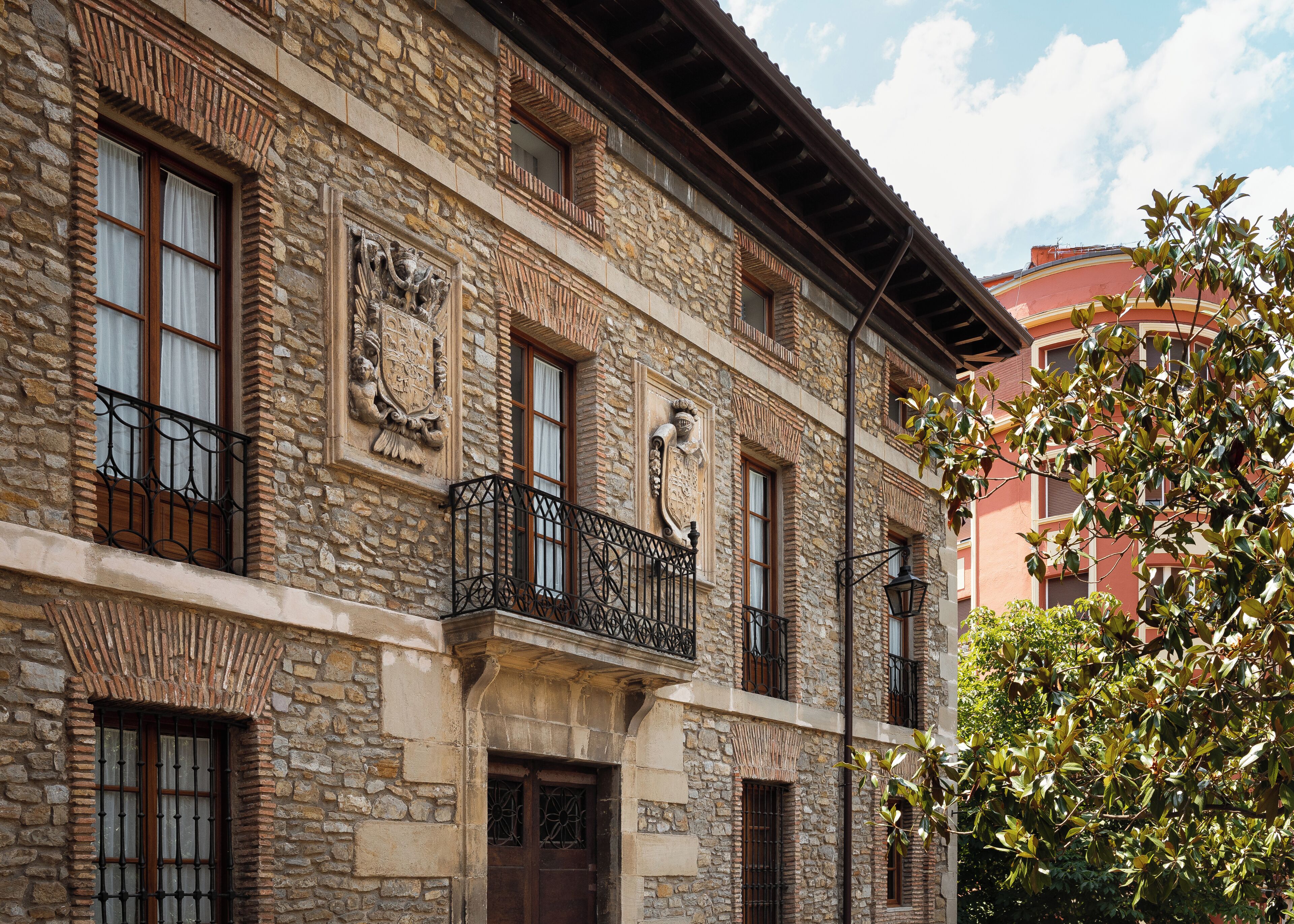 A stone building with multiple windows and balconies, featuring traditional architectural details.