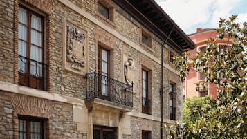 A stone building with multiple windows and balconies, featuring traditional architectural details.