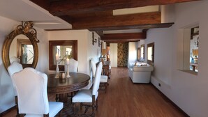 Un coin repas avec une table ronde en bois, des chaises à revêtement blanc et un grand miroir décoratif.