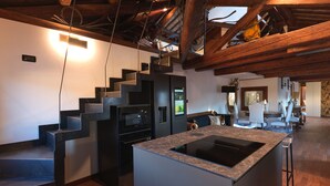 Une cuisine moderne dotée d’un îlot central, d’appareils électroménagers intégrés et d’un escalier en bois.