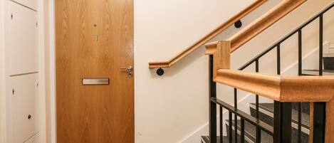 A wooden door with a metal handle and a small shelf above it.