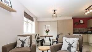 Un salon moderne avec deux fauteuils marron, une table basse en bois et un coin repas comprenant une table et des chaises.