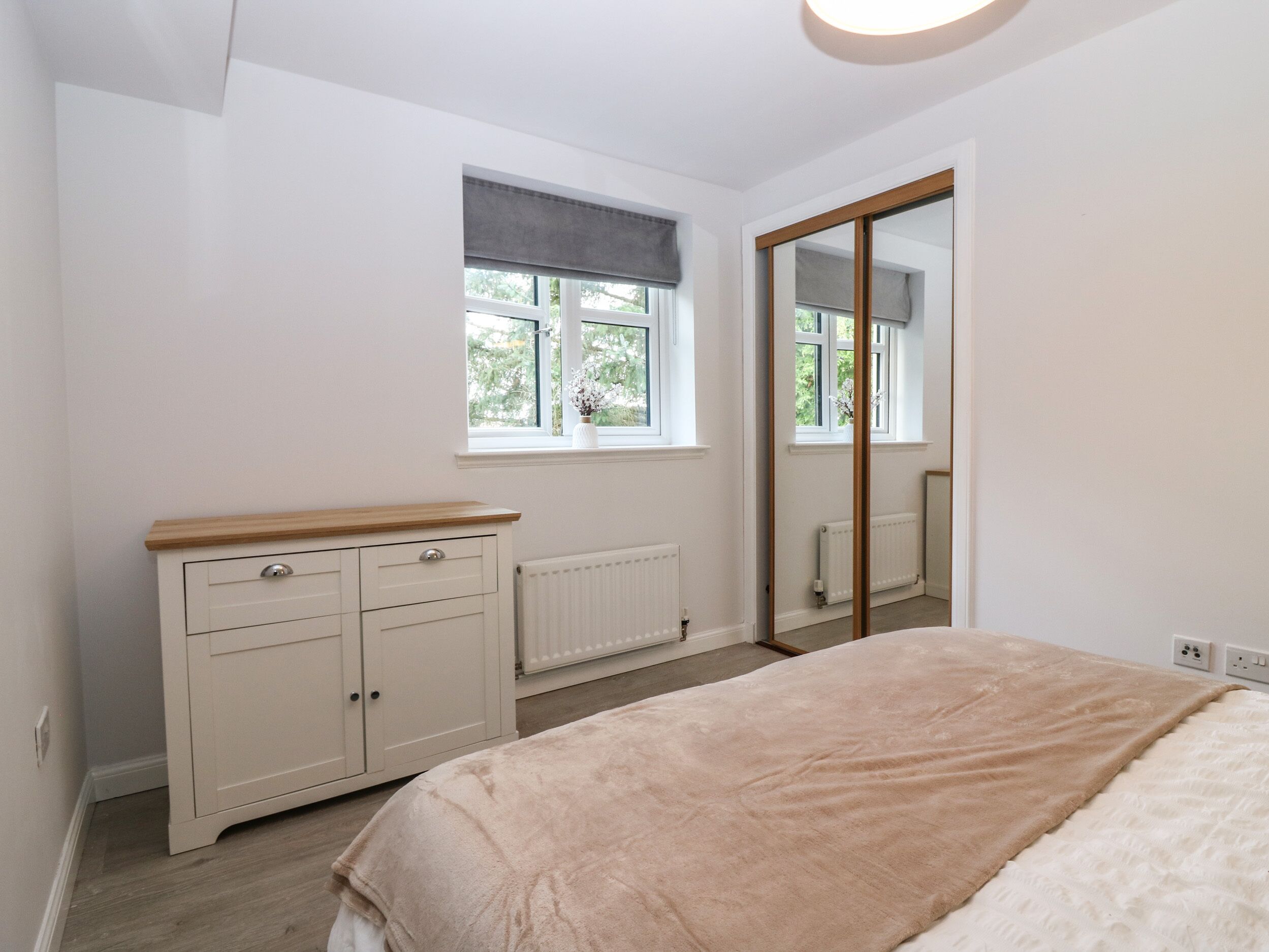 A bedroom with a bed, a wardrobe, a window, and a radiator.