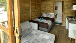 Une petite cabane en bois comprenant un lit, un canapé, un coin cuisine et une salle de bain.