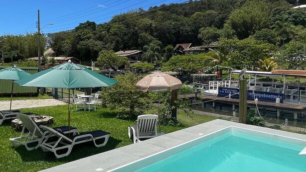 Une piscine entourée de verdure et de collines, avec des chaises longues et des parasols.