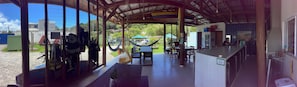 A covered outdoor area with tables and chairs, a view of the surrounding landscape, and a bar area with a counter and seating. - Floripa Glamping (Florianópolis)