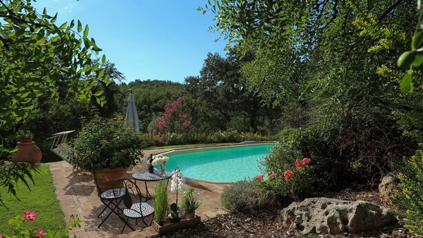 A private pool surrounded by lush greenery and a patio area with outdoor furniture. - Cammino Santo - studio w/private pool & garden (Poggibonsi)
